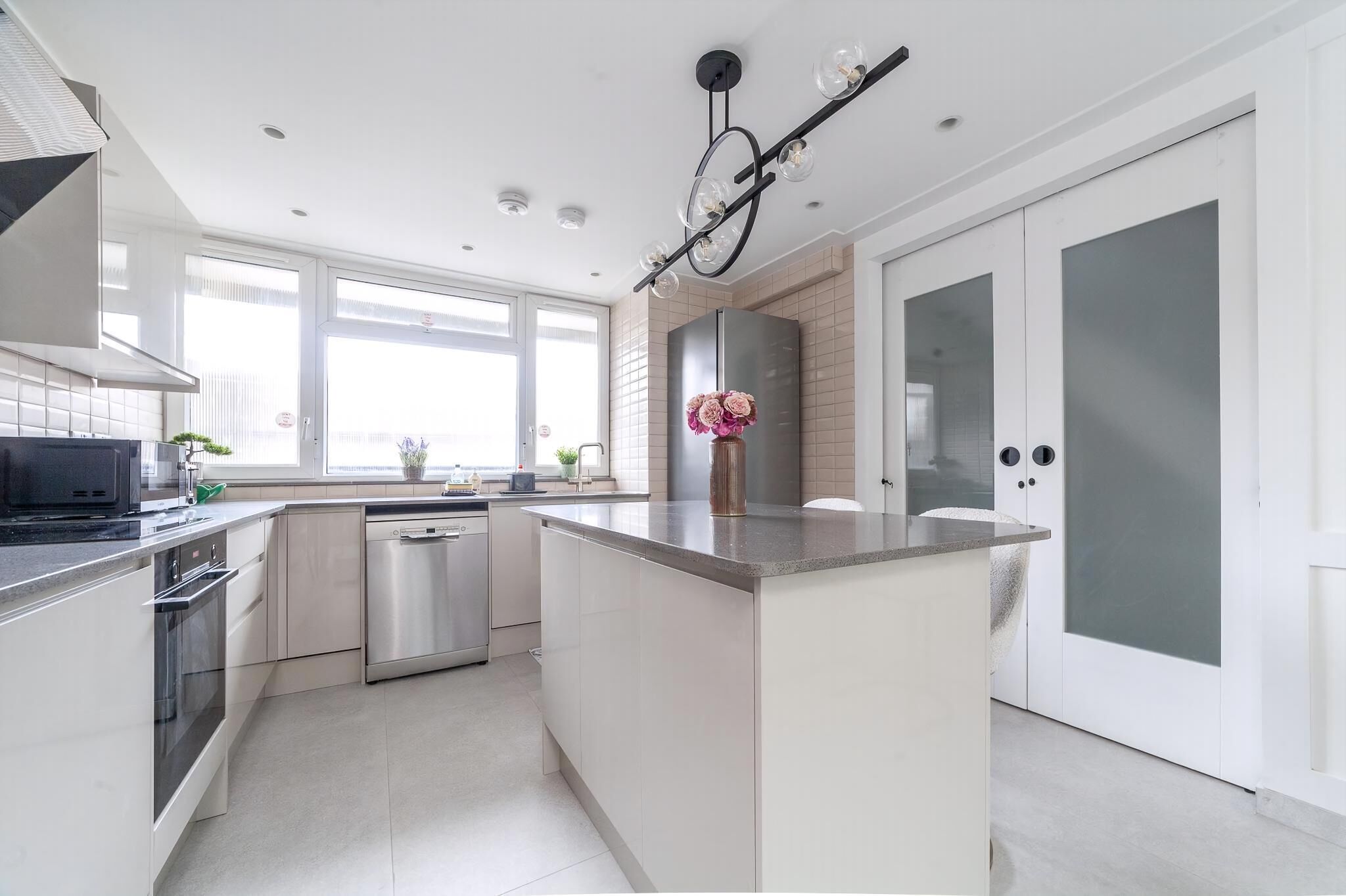 A modern kitchen with a central island, stainless steel appliances, and a large window providing natural light.