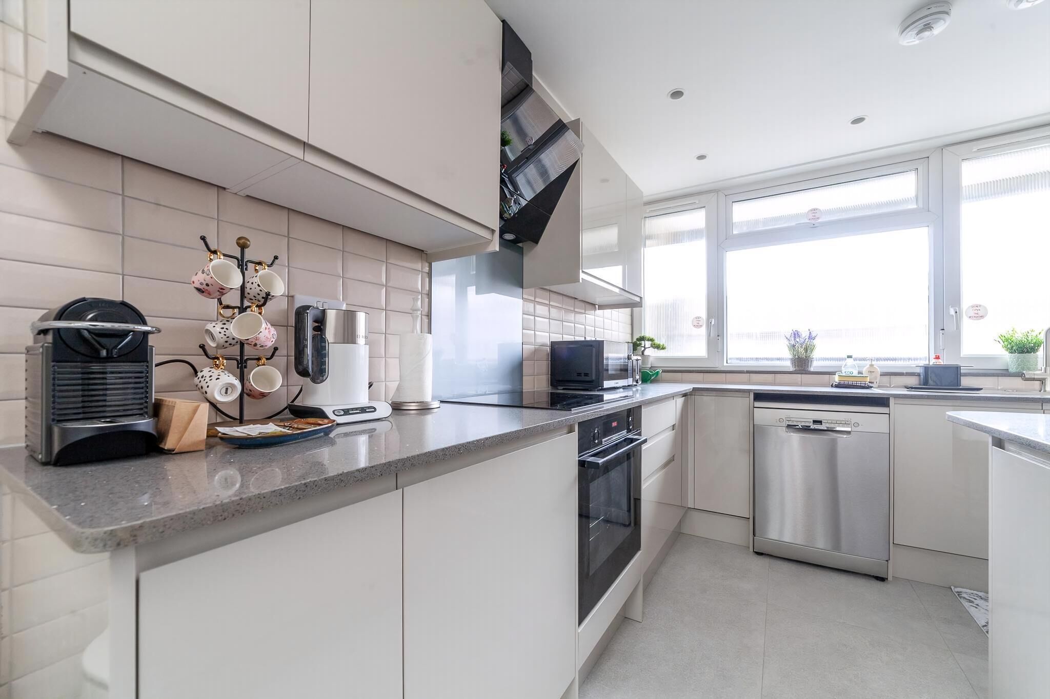 A modern kitchen with white cabinets, stainless steel appliances, and a window providing natural light.