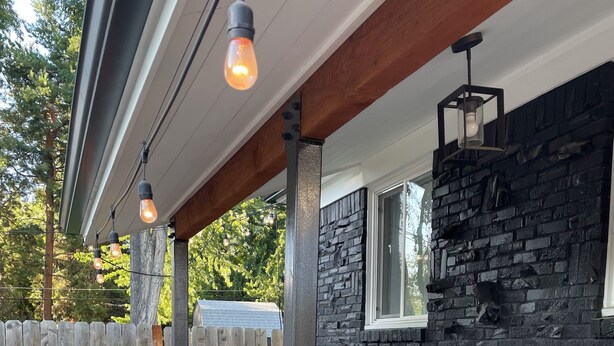 A modern outdoor deck with a wooden railing, a stone wall, and a metal fence.