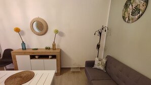 A living room with a wooden coffee table, a sofa with patterned cushions, a dining table with woven placemats, a wall-mounted mirror, and a decorative plant. - The Green Arch, located in the center of the seaside village of San Nicola l'Arena (San Nicola l'Arena)