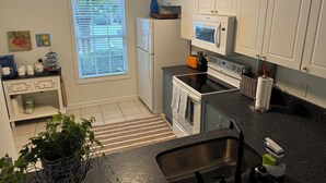 A kitchen with white cabinets, a refrigerator, a microwave, an oven, a sink, and a window with blinds. - Lovely 2BR 2.5BA Condo (Auburn)