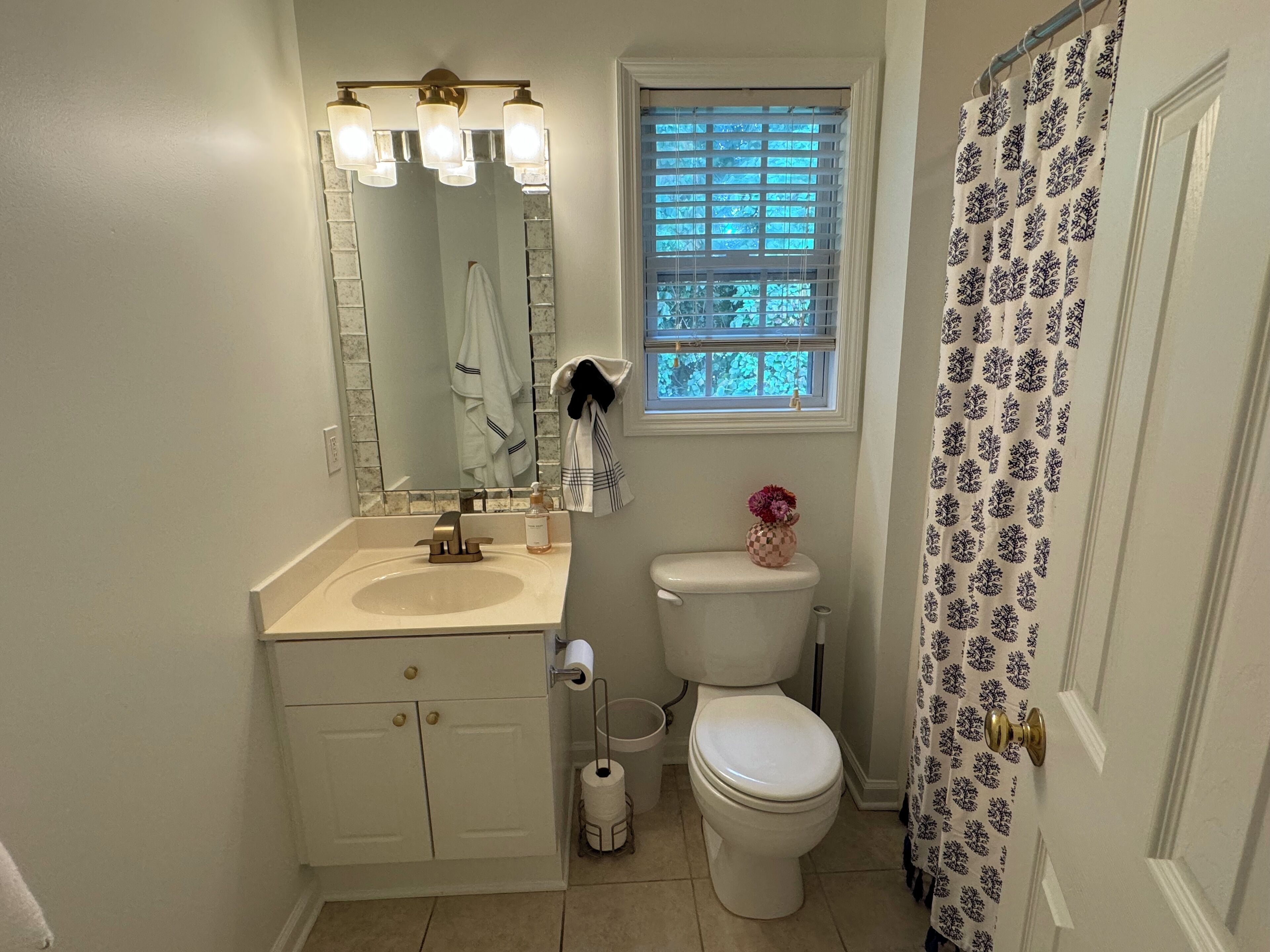 A bathroom with a sink, toilet, and a window with blinds.