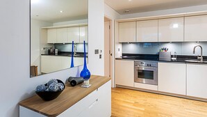 A modern kitchen with white cabinets, stainless steel appliances, and a wooden countertop. - Perfect Paddington Pad (London)