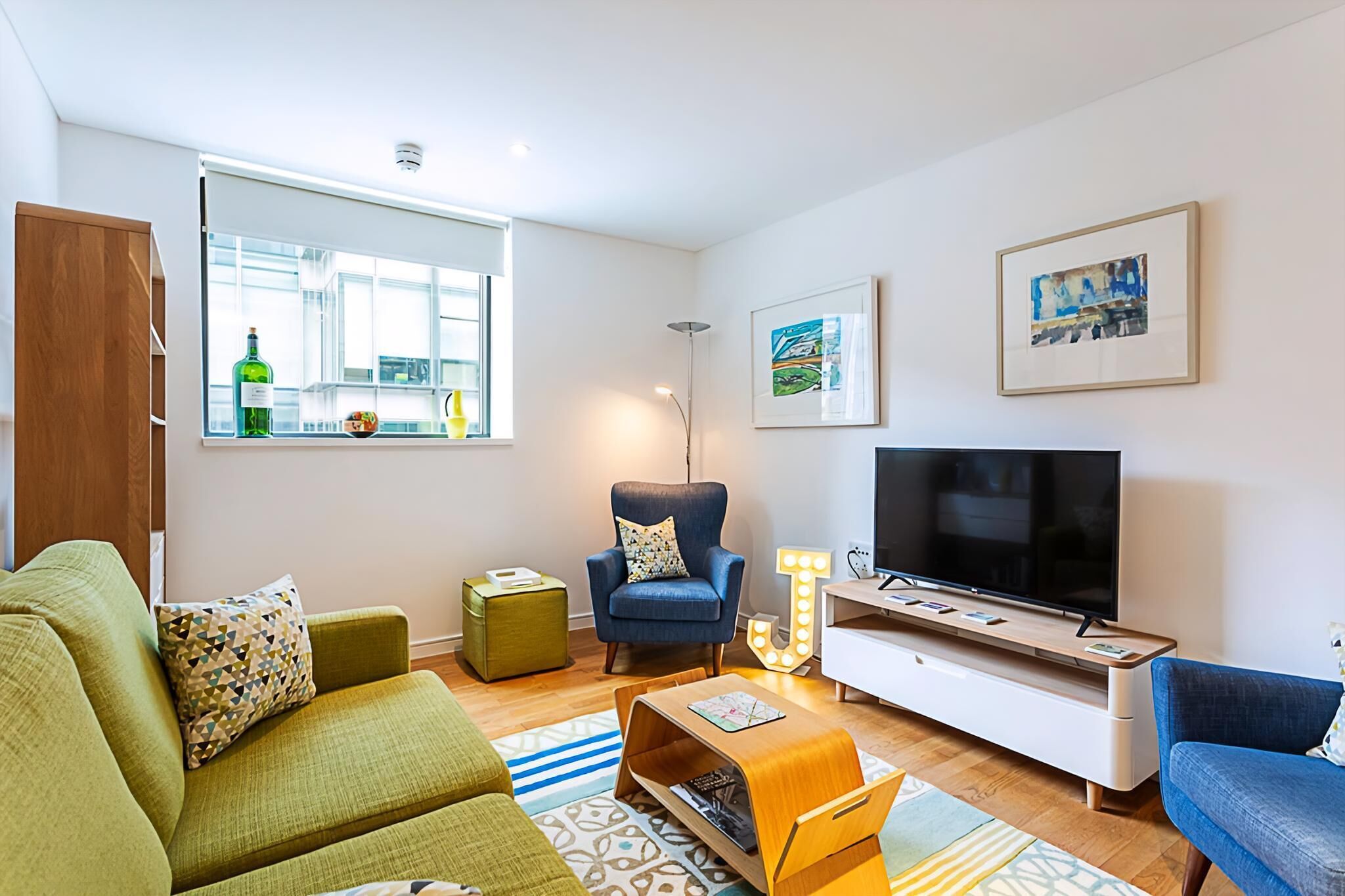 Una sala moderna con sofá, sillón, televisor y una mesita.