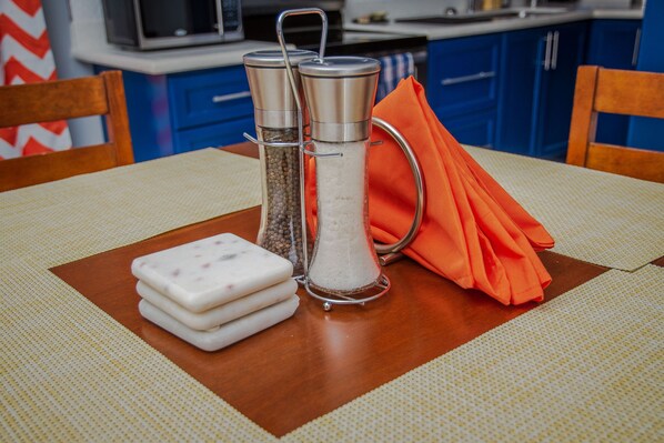 A kitchen with blue cabinets, a wooden chair, and a table with salt and pepper shakers.