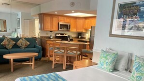 Una habitación de hotel con cama, sofá, mesa de comedor y zona de cocina.
