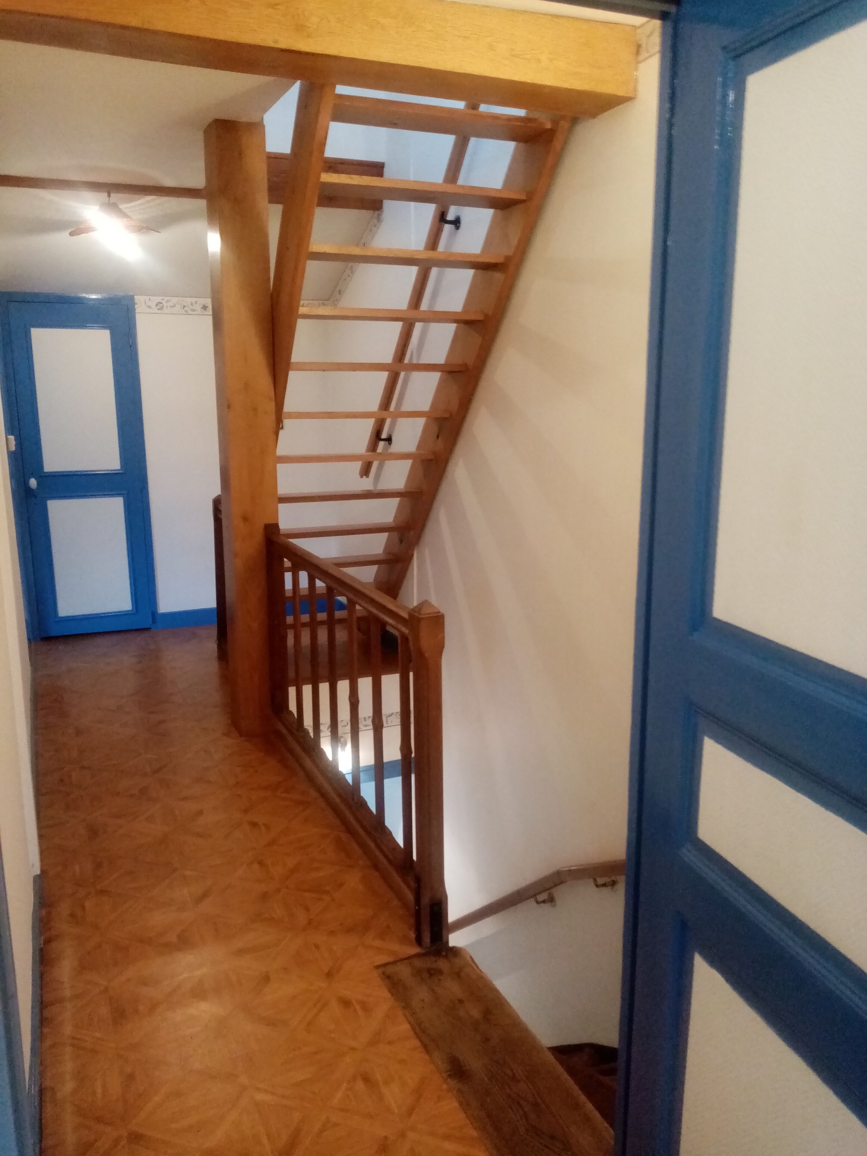 A wooden staircase with a metal railing leading to a landing.