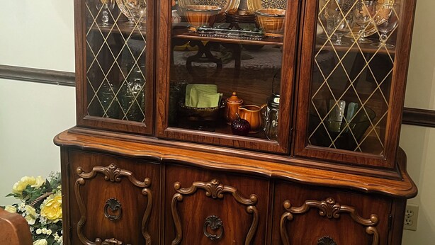 A wooden display cabinet with glass doors, containing various ceramic dishes and glassware. - Groovy 1970s Home in central Indiana with basement full of entertainment! (Carmel)