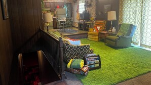 A cozy living room with a staircase, a dining area, and a kitchen in the background. - Groovy 1970s Home in central Indiana with basement full of entertainment! (Carmel)