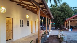Un bâtiment avec des portes et des fenêtres en bois, un espace extérieur couvert agrémenté de guirlandes lumineuses et de plantes en pot.