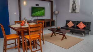 Una sala de estar moderna con comedor, televisor de pantalla plana y un sofá con cojines estampados.