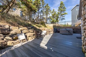 Une terrasse en bois avec des meubles dâextĂ©rieur, un mur en pierre et une maison en arriĂšre-plan.