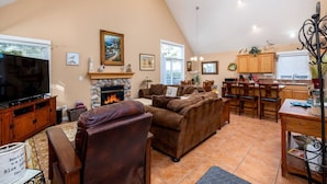 A spacious living room with a fireplace, a television, and a dining area with wooden furniture.