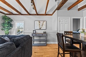 A room with a dark gray sofa, a wooden dining table, and a white door. - Rustic Charm 2BR Downtown Burl. (Burlington)