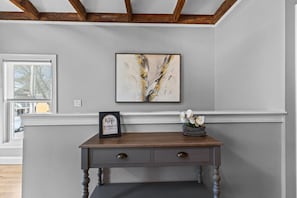 A room with a wooden console table, a framed picture, and a vase with flowers. - Rustic Charm 2BR Downtown Burl. (Burlington)