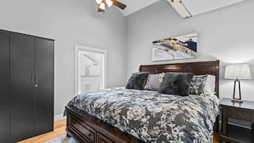 A bedroom with a bed, a ceiling fan, a nightstand, a lamp, and a wardrobe.