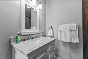 Une salle de bain avec un lavabo en marbre, un grand miroir et un porte-serviettes.