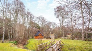 A wooden bridge leading to a rustic cabin in a forested area. - 5 bedroom accommodation in Nethy Bridge (Nethy Bridge)