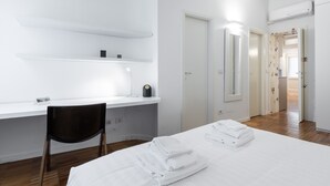 A hotel room with a bed, a desk with a chair, a mirror, and a door leading to another room. - Italianway Easy - Farini 2 (Milano)