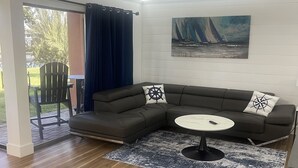 A modern living room with a sectional sofa, a round coffee table, and a ceiling fan. - Updated Lakeview condo in Gated community close to beach.  (Destin)
