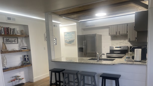 A modern kitchen with a granite countertop, stainless steel appliances, and wooden flooring. - Updated Lakeview condo in Gated community close to beach.  (Destin)