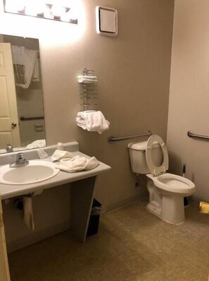 Bathroom features a sink, mirror, toilet with raised seat, and towel rack.