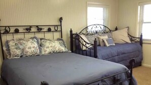 Un dormitorio con dos camas, una con cubrecama floral y la otra con cubrecama azul lisa.