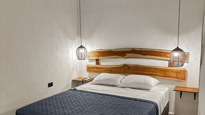 A bedroom with a bed, wooden headboard, bedside tables, and hanging pendant lights.