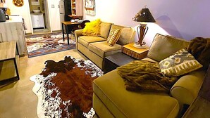 En stue med sofa, sofabord, lampe og en måtte af kohide.