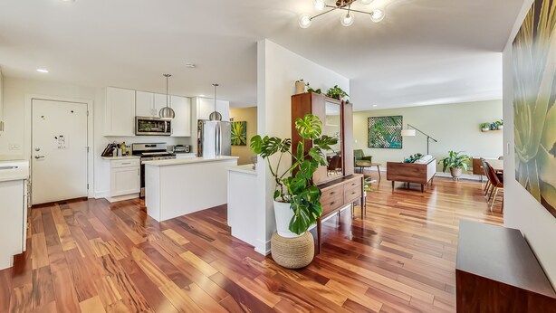 Une cuisine moderne avec des meubles blancs, un îlot central et un coin repas comprenant une table et des chaises en bois.