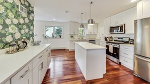 Une cuisine moderne avec des armoires blanches, des appareils en acier inoxydable et un plancher en bois.