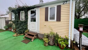 Een gelijkvloers huis met een nummer 27, een voordeur en een klein portaal met treden.