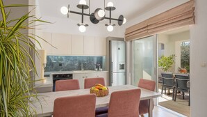 Een moderne keuken met een marmeren aanrechtblad, roestvrijstalen apparatuur en een eethoek met een marmeren tafel en beklede stoelen.