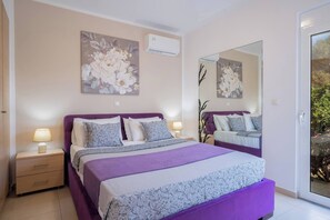 A bedroom with a large bed, two bedside tables, a mirror, and floral artwork on the walls.