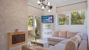 Een moderne woonkamer met een open haard, een bank, een salontafel en een televisie aan de muur.