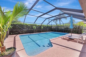 A swimming pool with a glass enclosure, surrounded by lounge chairs and a palm tree. - Pure Living, Saltwater Pool, Low Toxin Getaway! (Port St. Lucie)