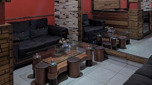A modern living room with a black leather sofa, a glass coffee table, and wooden accents. - URBAN VIBER MOTEL (Kigali)
