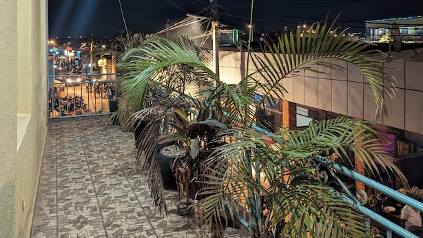 A rooftop terrace with tiled flooring, potted plants, and a view of the cityscape at night. - URBAN VIBER MOTEL (Kigali)