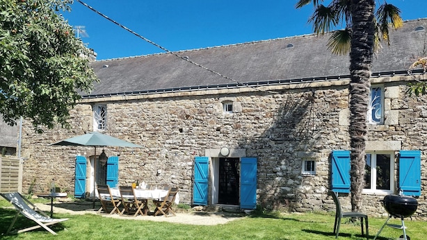 Un edificio de piedra con un patio, mobiliario exterior y una parrilla.