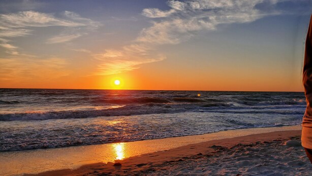 Un coucher de soleil sur l’océan, avec des vagues qui se brisent sur le rivage.