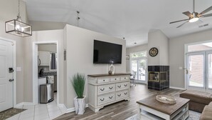 A spacious living room with a large flat-screen TV, a wooden coffee table, a beige sofa, and a fireplace. - Castle Glow - 2BR - BBQ Gr - Walk to Kroger Field (Lexington)