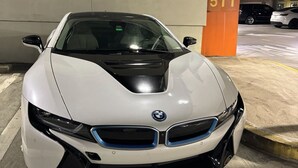 Une BMW blanche est garée dans un garage portant l’enseigne « Dolphin Garage » et l’inscription « 5TT ».