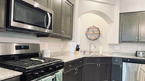 A modern kitchen with stainless steel appliances, dark cabinetry, and a granite countertop. - Best 3-Story Home in Vegas - 9mins to Everything! (Las Vegas)