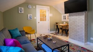 A living room with a sofa, a coffee table, a TV, and a dining area with chairs and a table. - Freshwater Flat, Downtown Douglas - Apart in Downtown right off Center Street. (Douglas)