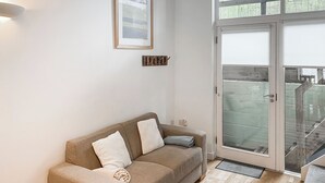 A neutral-toned living room with a beige sofa, two white cushions, and a framed picture on the wall.