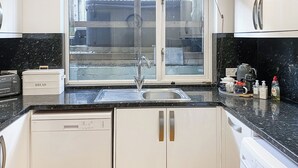 A kitchen with a window, a sink, a toaster, and a bread box.