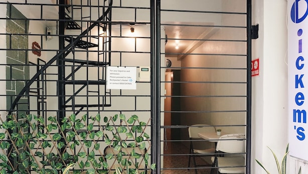 L’entrée d’un hôtel est ornée d’un portail en métal, d’un escalier et d’un panneau indiquant aux personnes intéressées où s’adresser pour obtenir des renseignements sur l’auberge de jeunesse Cebu Backpacker’s Hostel.