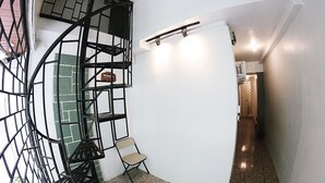 Un escalier en colimaçon avec une rampe métallique, un tableau blanc et une chaise pliante dans un couloir.