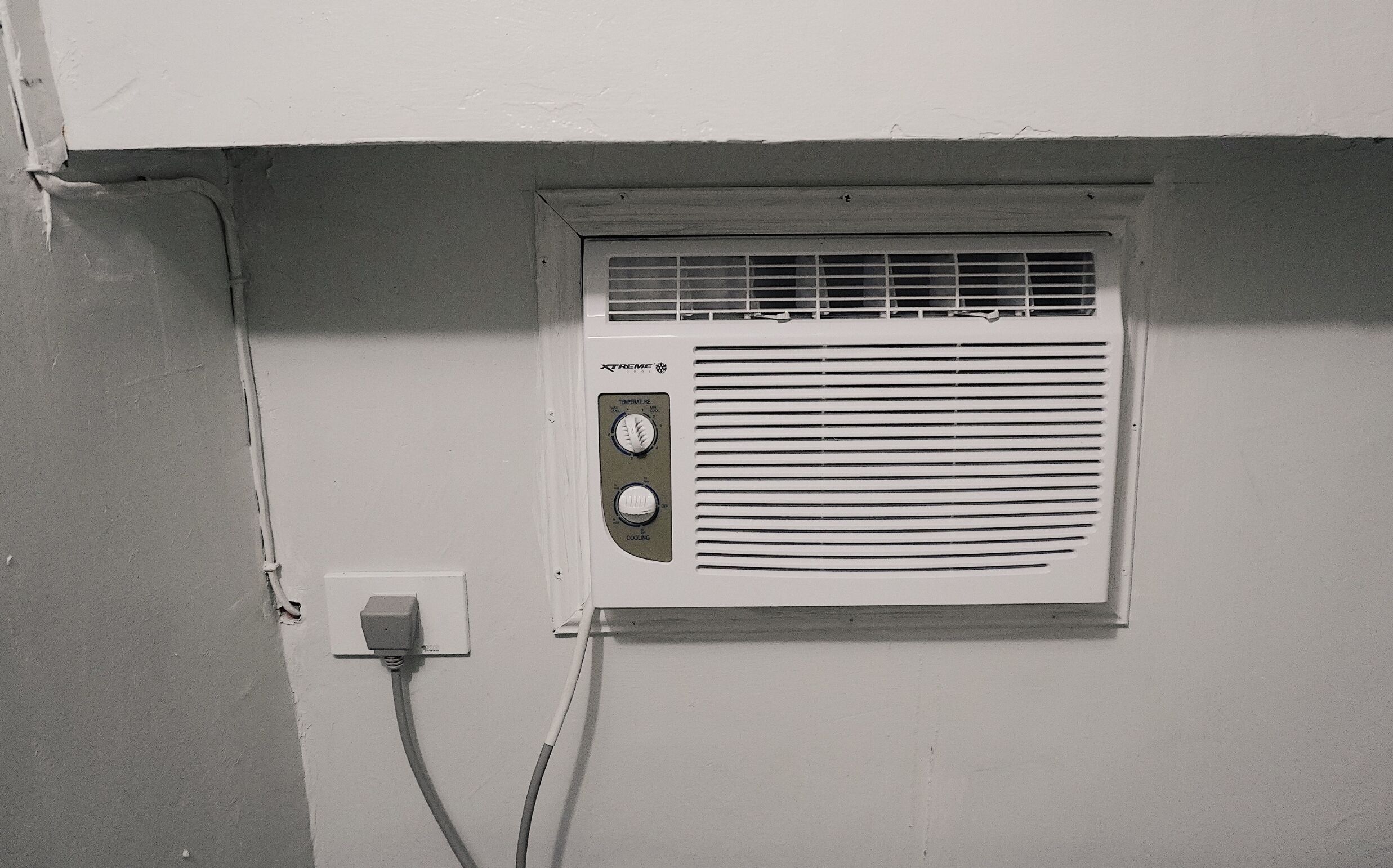 Un equipo de aire acondicionado instalado en la pared, con un panel de control y un cable de alimentación.