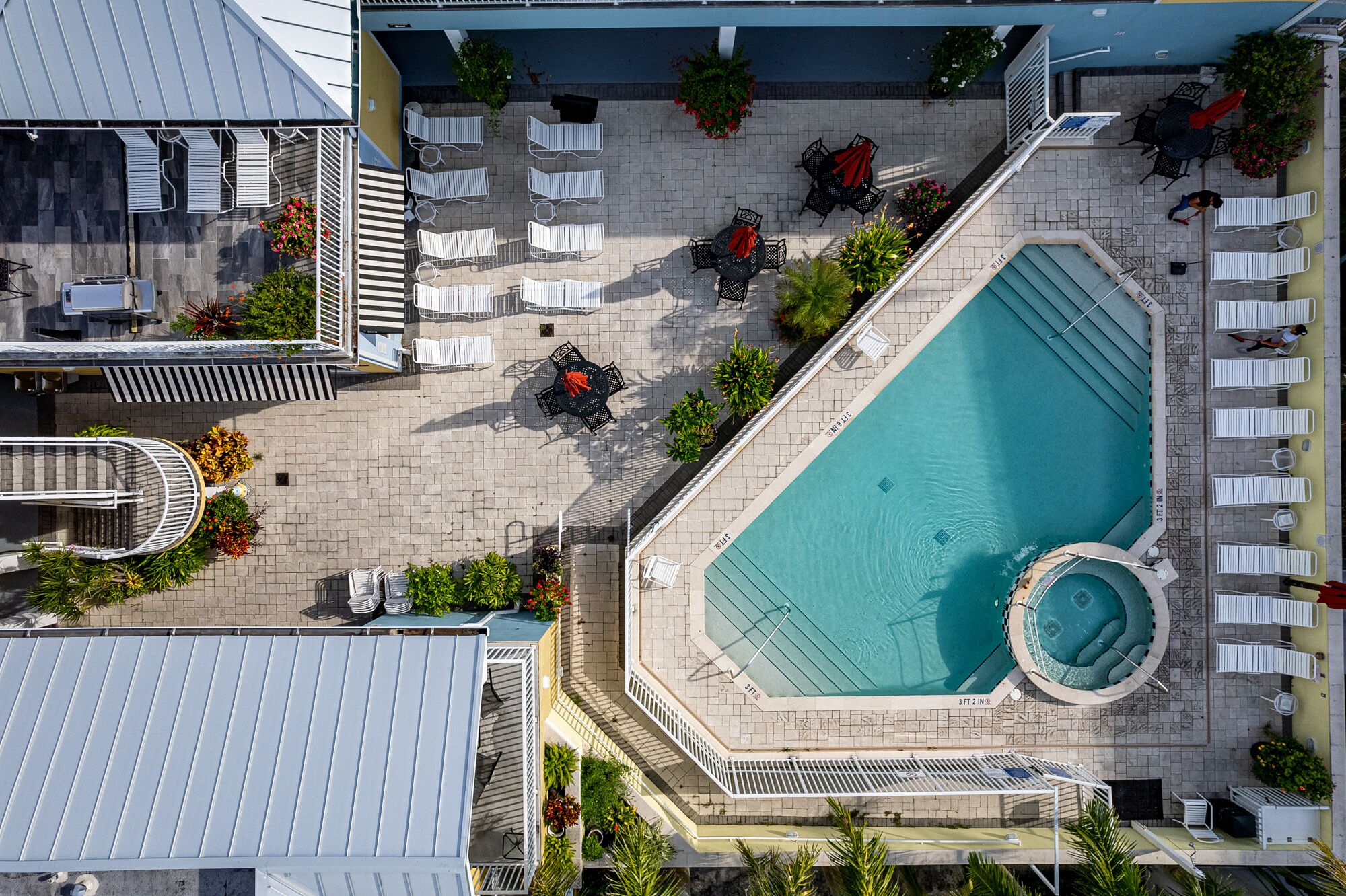Vista aérea de un hotel con piscina, tumbonas y un área de patio techada.